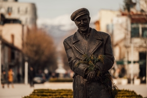 A bronze statue of a man holding flowers on a street in Niksic